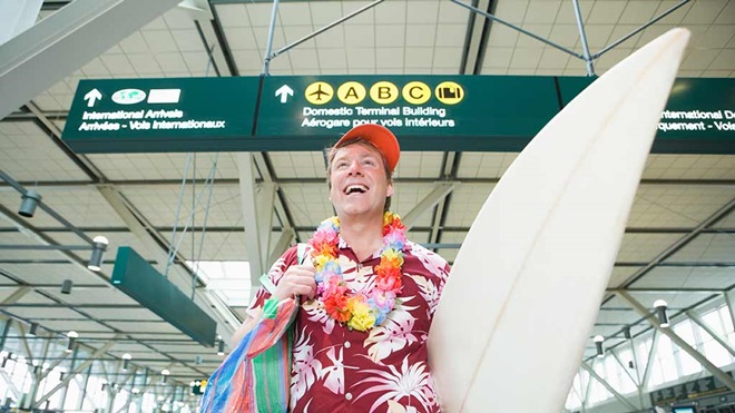 man with surfboard walking through airport